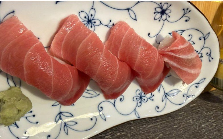 Piezas de nigiri de atún sobre un plato de porcelana